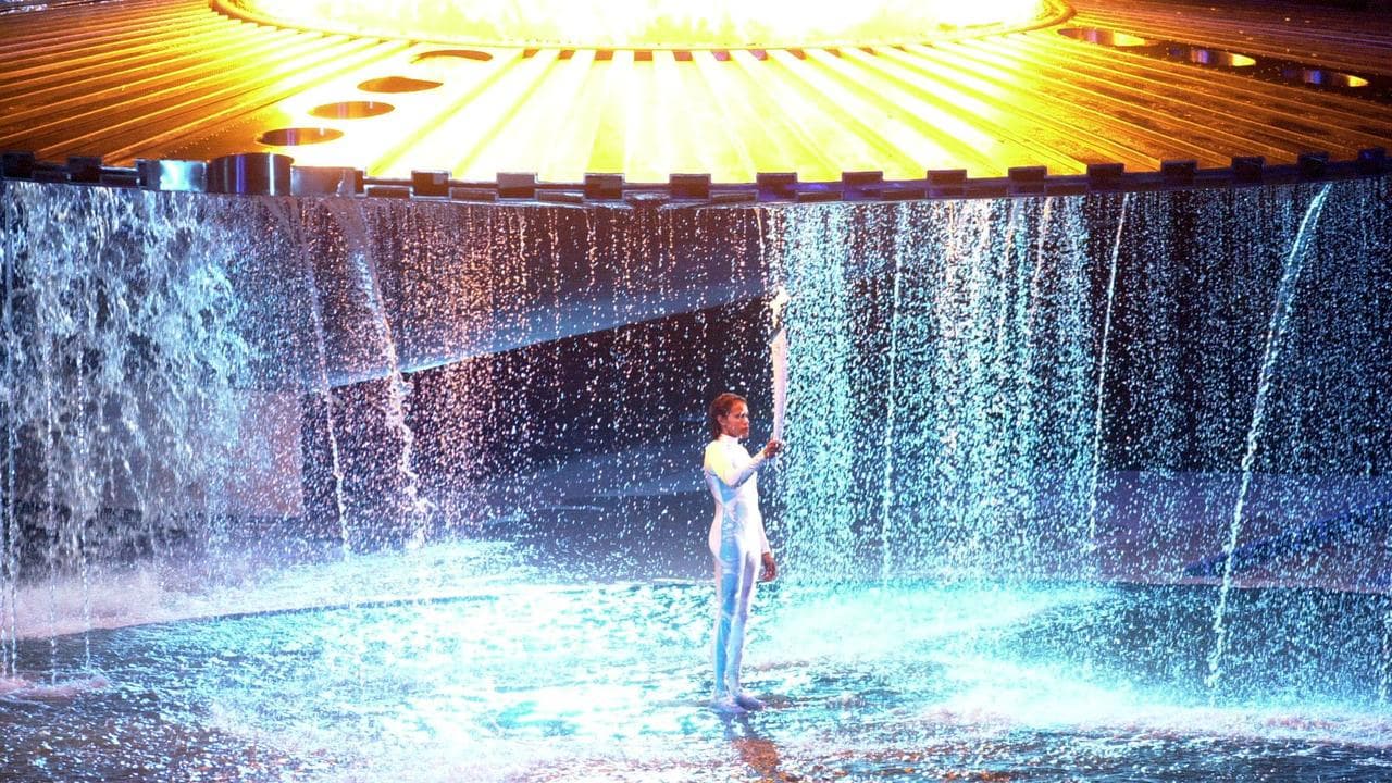 Cathy Freeman  stands beneath the Olympic flame