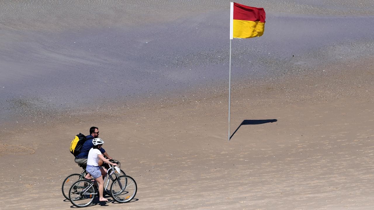 Cyclists ride on the beach at Main Beach