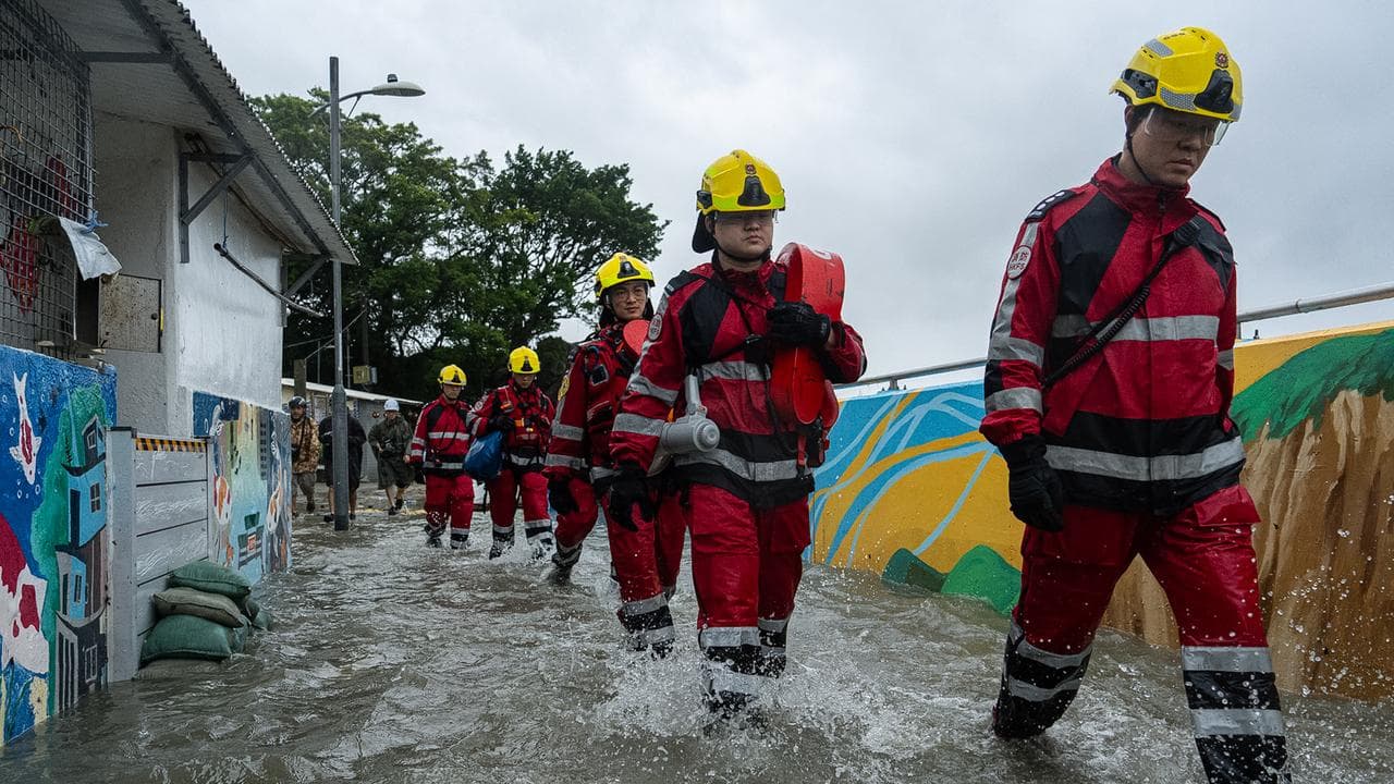Firefighters walk through the floodwaters in Hong Kong