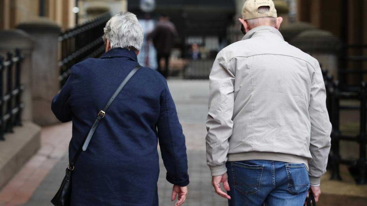 An elderly couple walking down a street