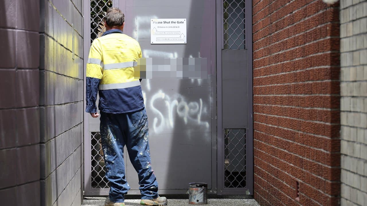 Worker removes graffiti from a door (file)