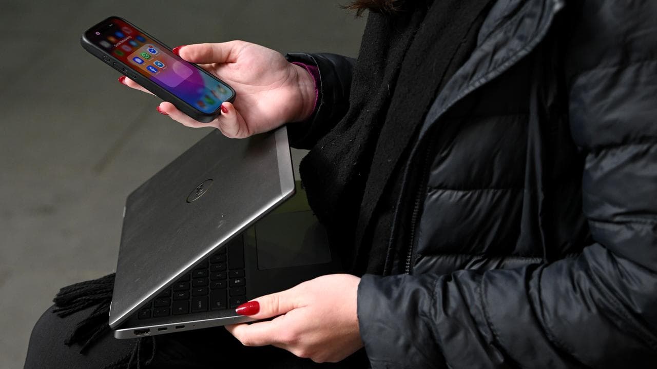 Generic image of a person holding a mobile phone and laptop