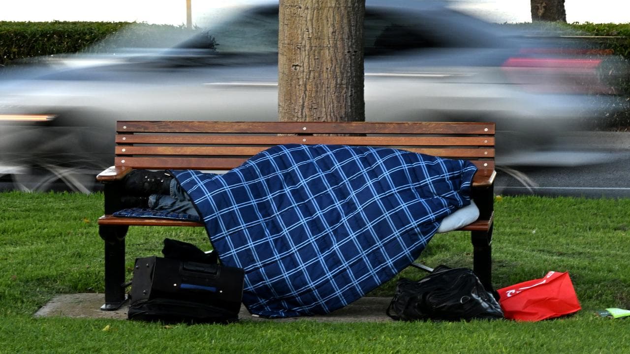 A homeless person sleeping on a park bench