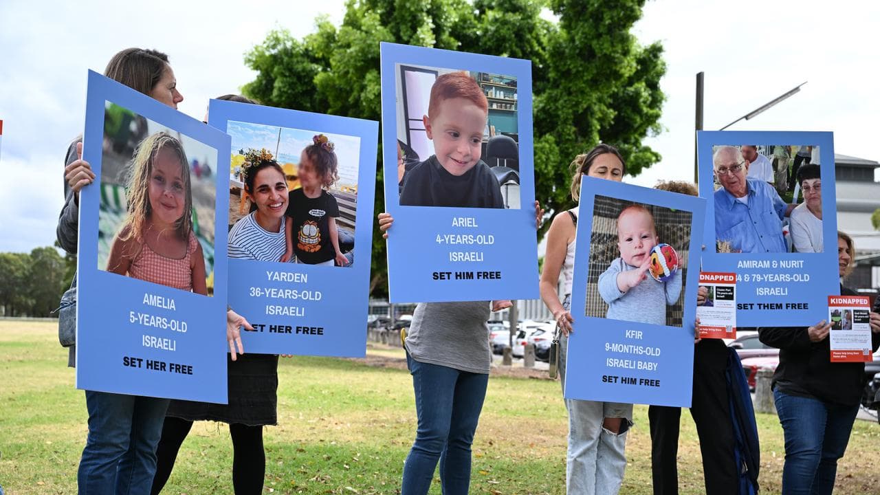 People hold up photos of hostages taken on October 7