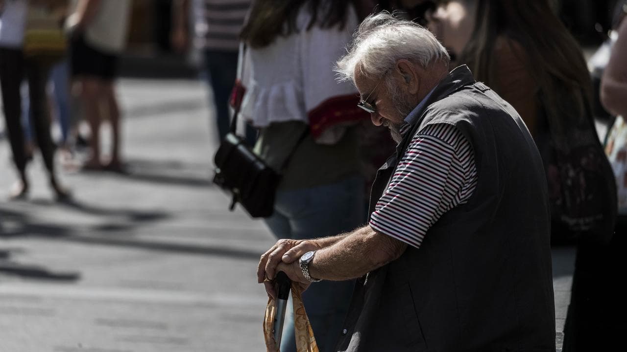 An elderly man sits on a bench