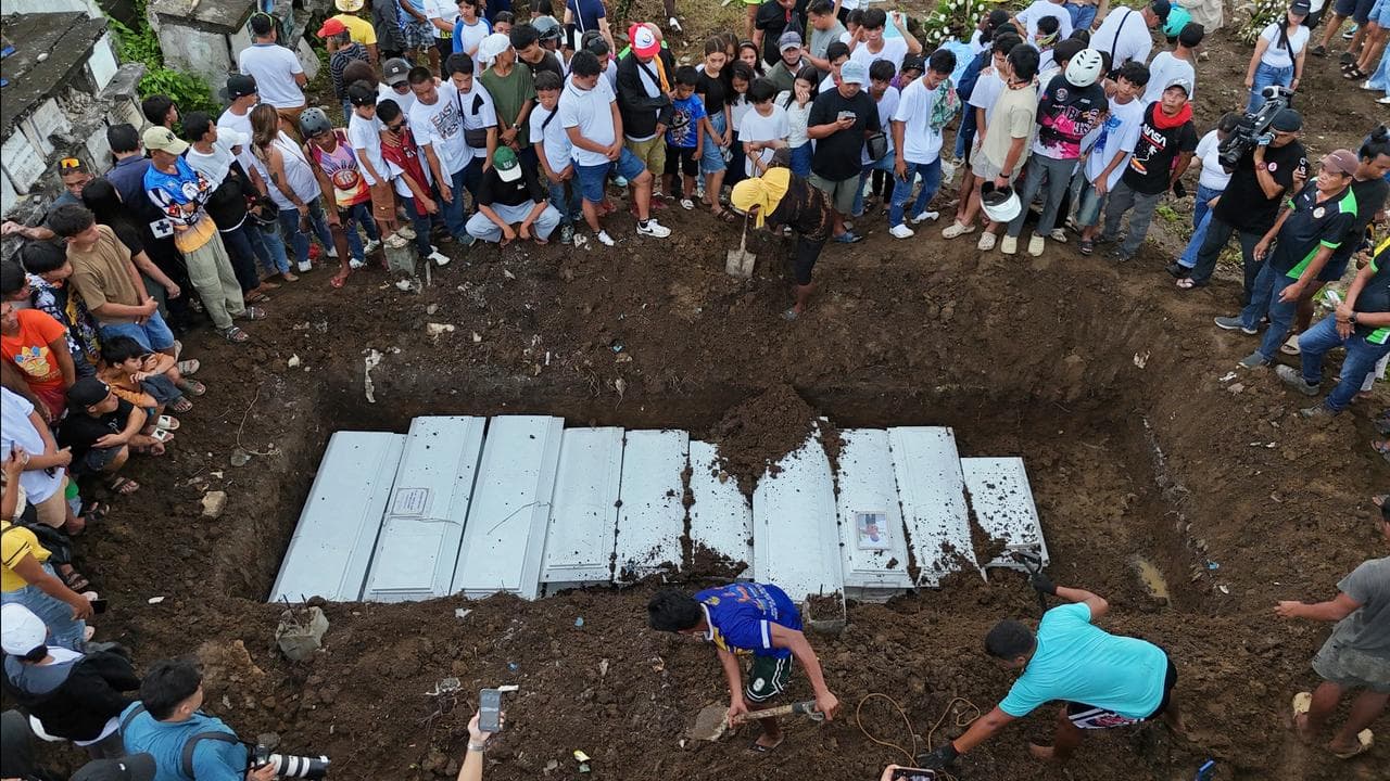 Families gather during the burial of earthquake victims in Cebu