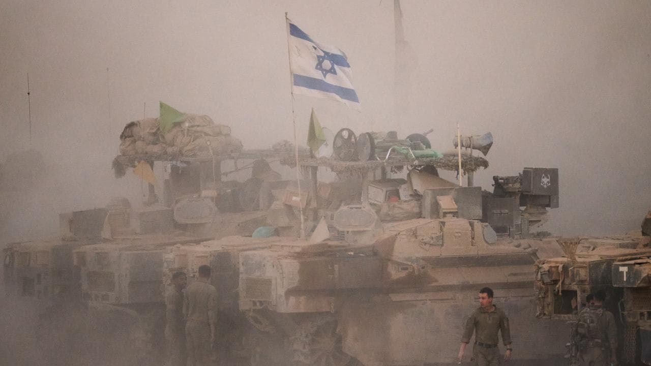 Israeli soldiers stand near their tanks along the Israeli-Gaza border