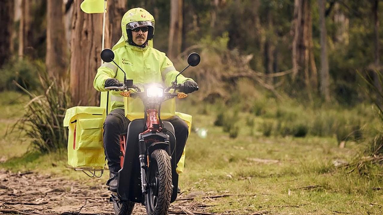 Australia Post employee delivers mail on an electric motorbike