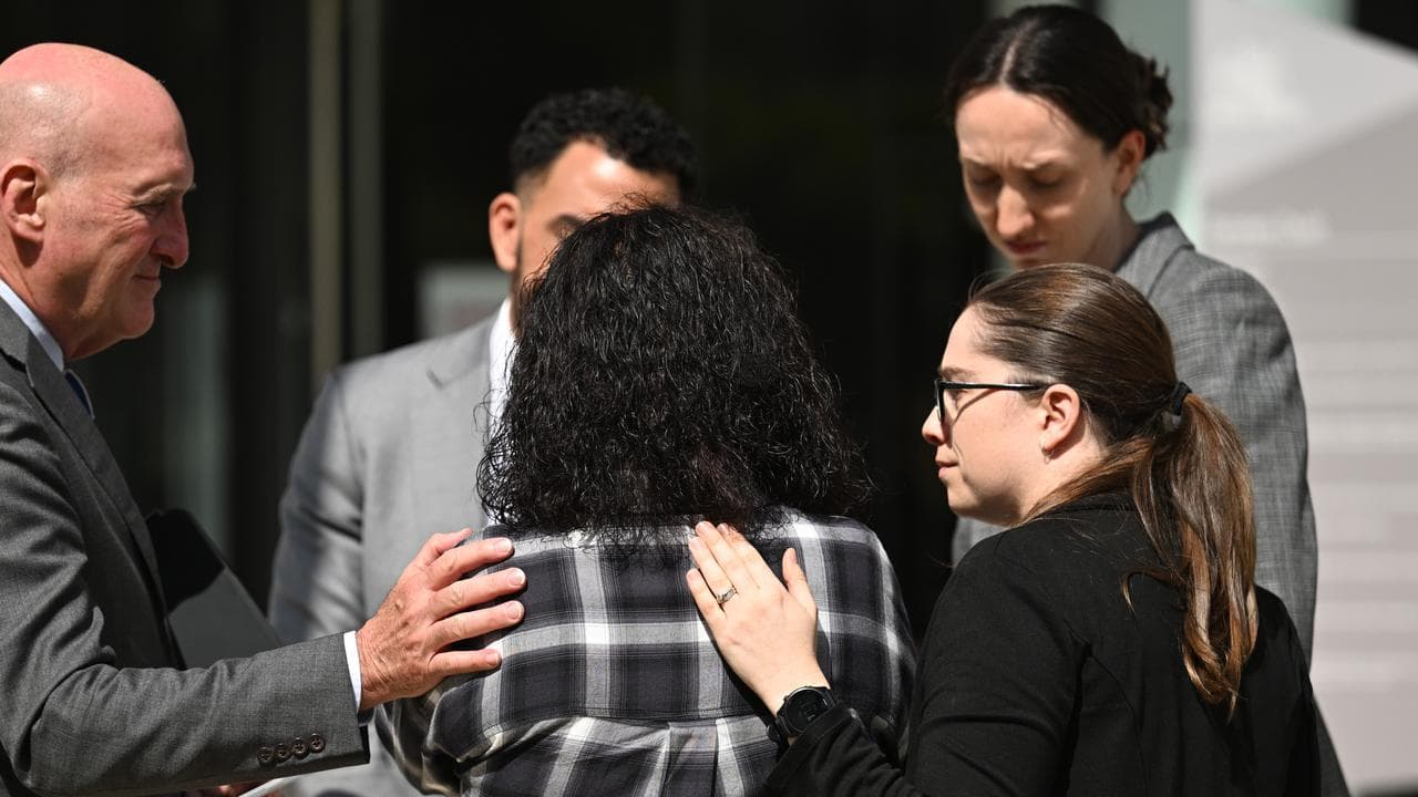Lorna Haines (back to camera) is comforted by her legal team
