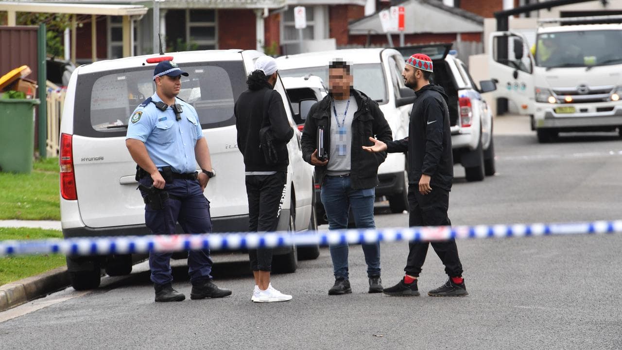 Police speak with residents at the scene of a shooting (file image)