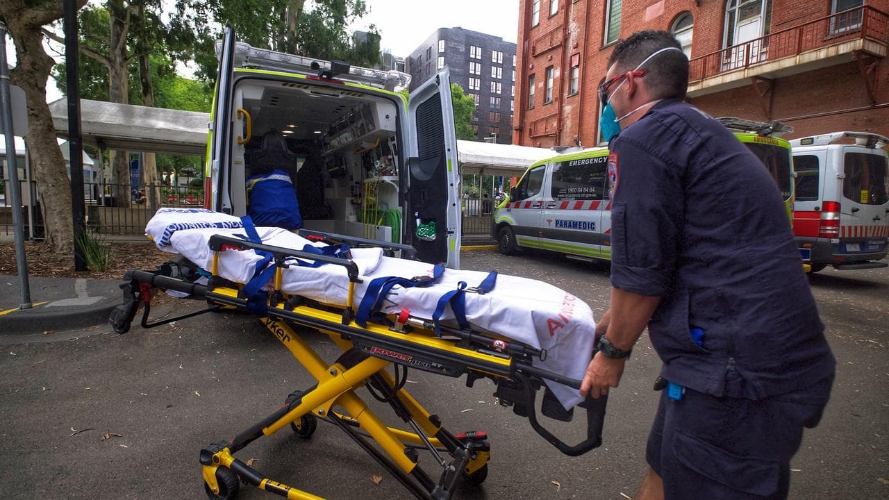 A paramedic places a stretcher in the back of an ambulance.