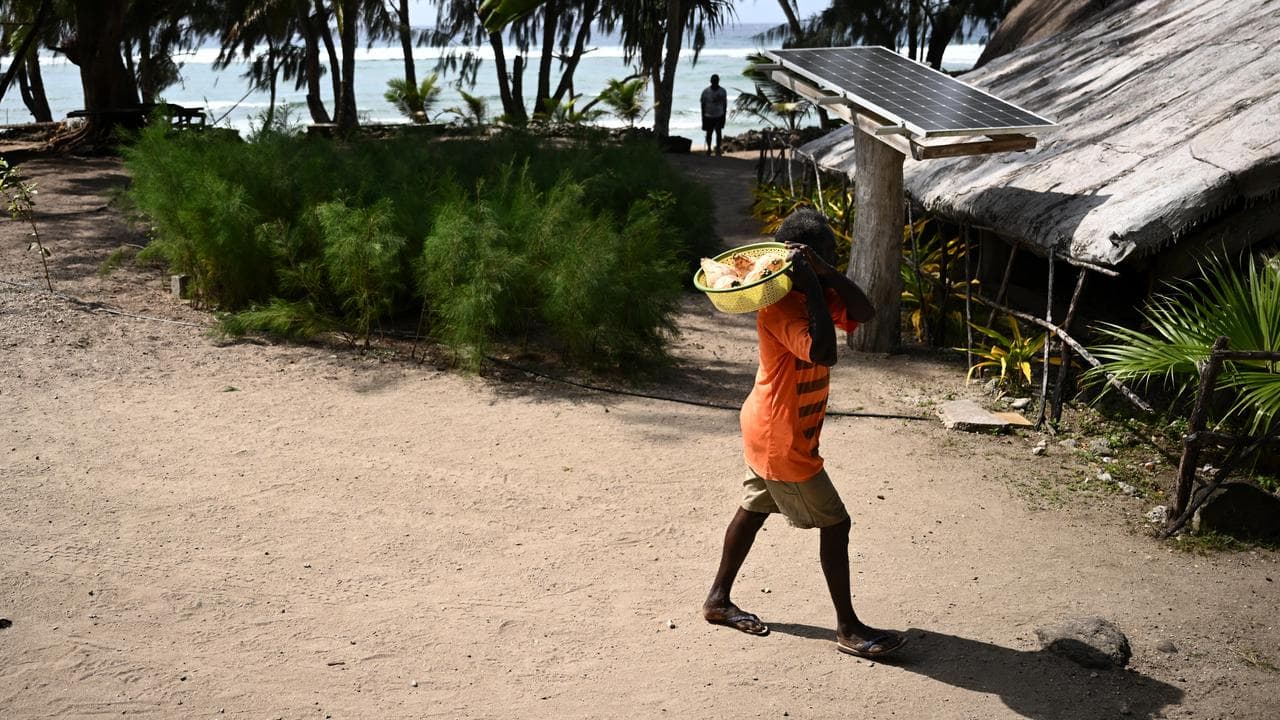 A man passes a solar panel in Vanuatu (file image)