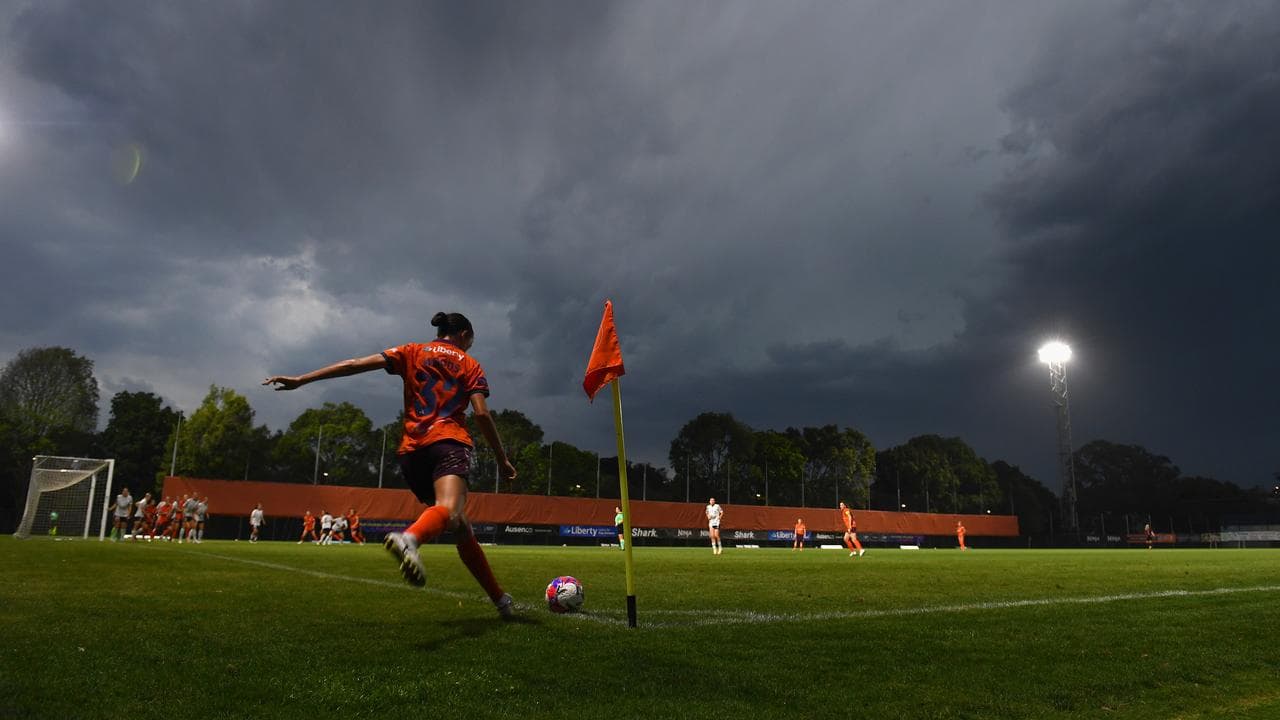 A photo of a footballer taking a corner with storm clouds approaching.