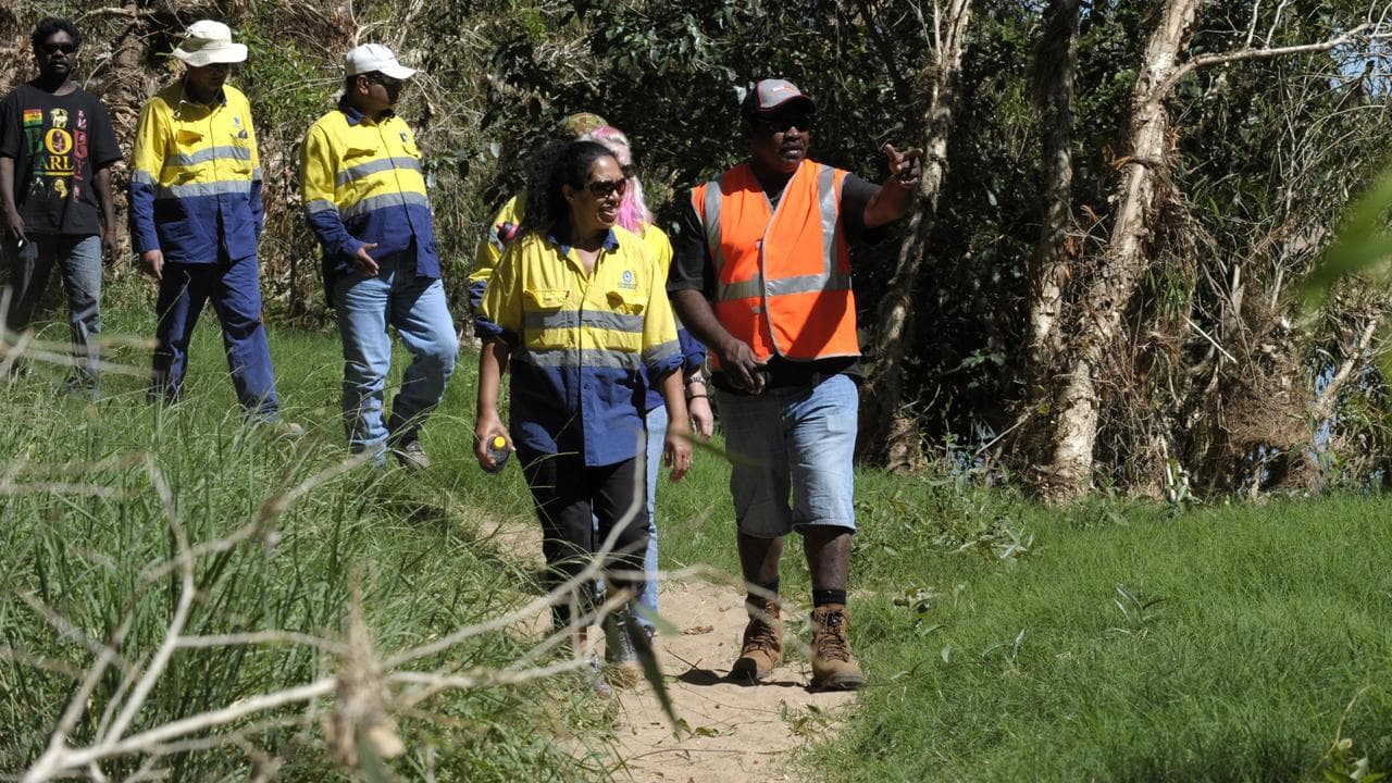 A photo of a traditional owner walking with mining company workers.