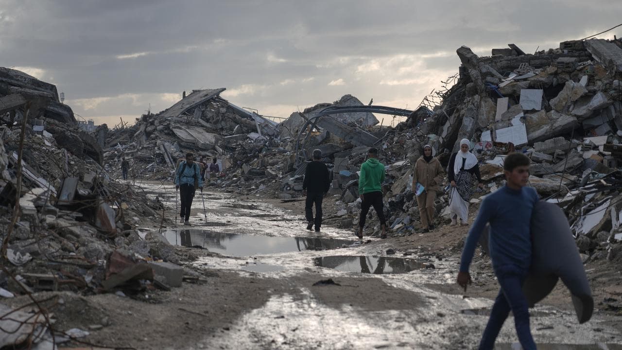 People walk among the ruins of destroyed buildings north of Gaza City