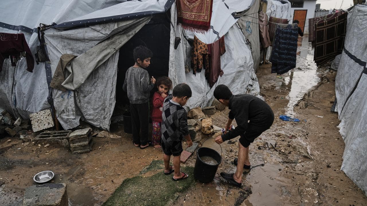 Palestinians clear water from their flooded tent in Gaza City