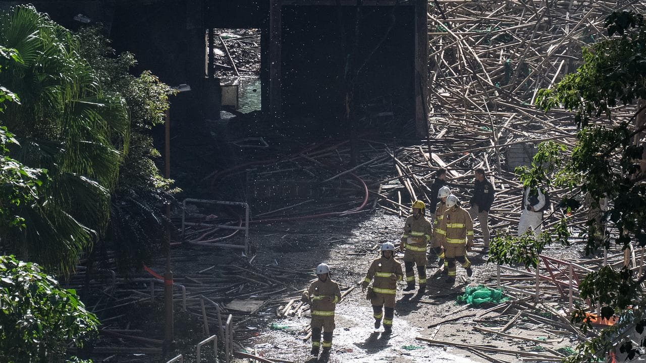 Firefighters walk through the burned buildings at Wang Fuk Court