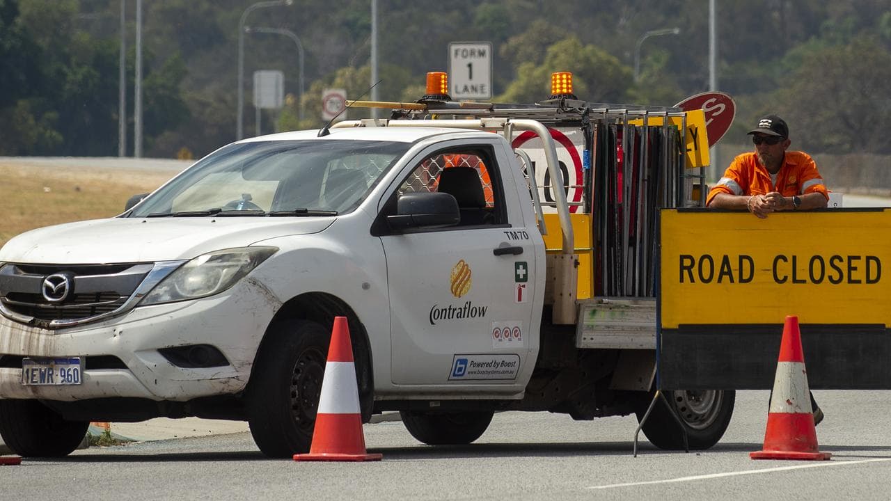 A worker blocks a road as firefighters attempt to control a blaze