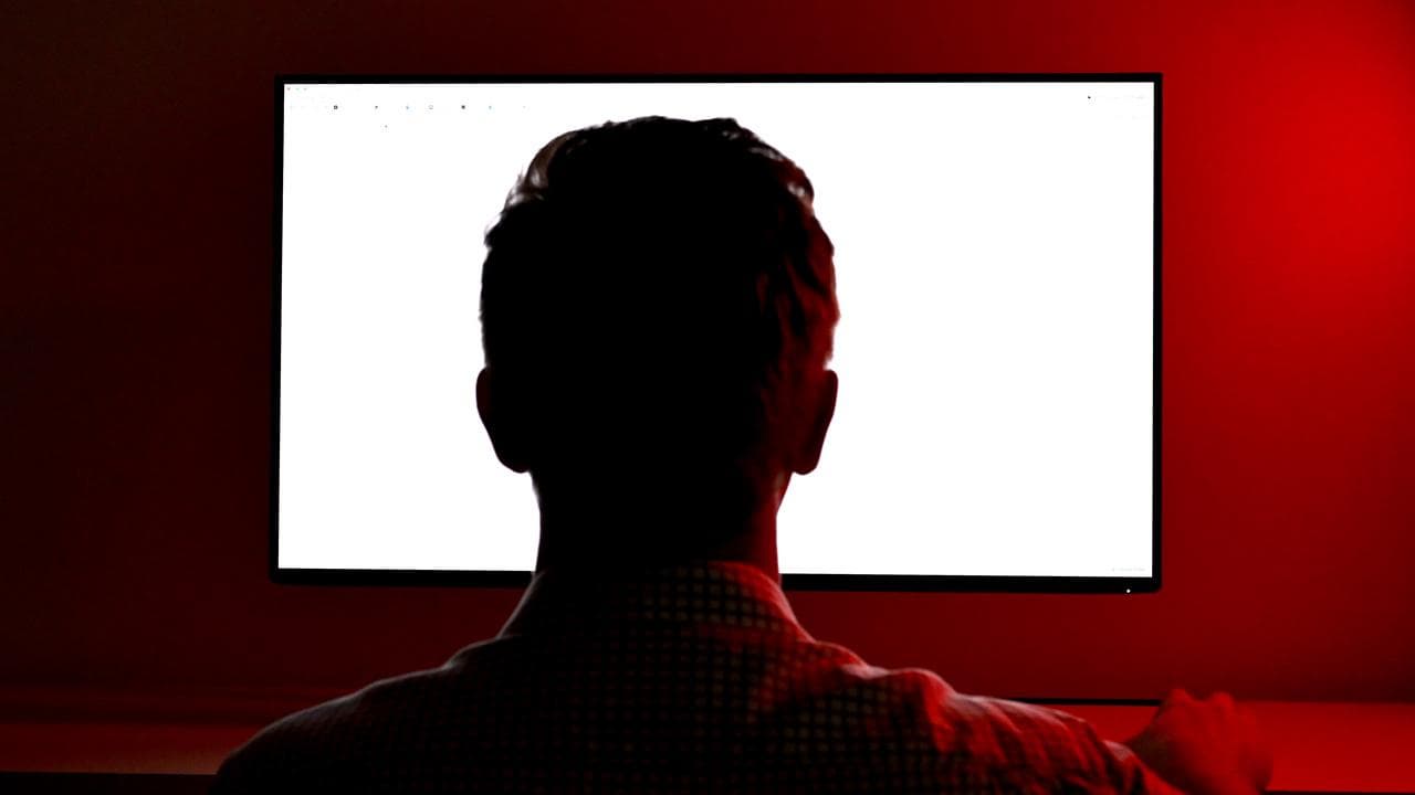 A photo illustration of a man looking at a screen