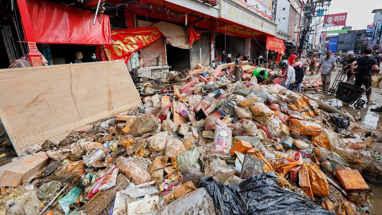 Peoples walk near goods damaged from floods in Songkhla province