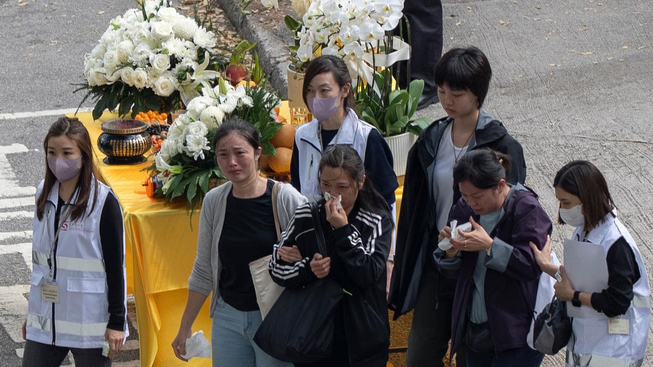 Relatives of victims weep after laying flowers at Wang Fuk Court