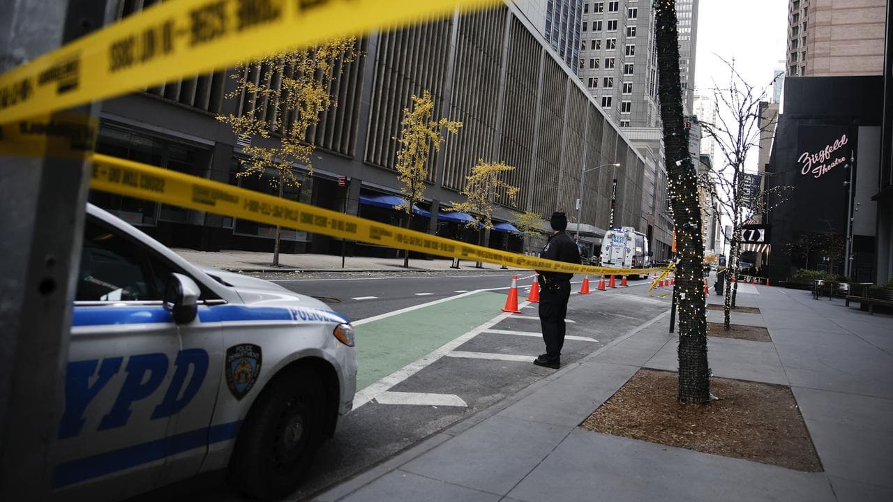 A police officer stands outside where Brian Thompson was shot