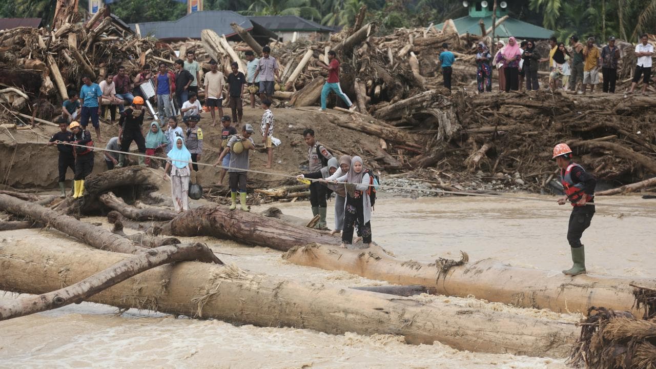 Flood survivors use logs to cross a river in North Sumatra, Indonesia