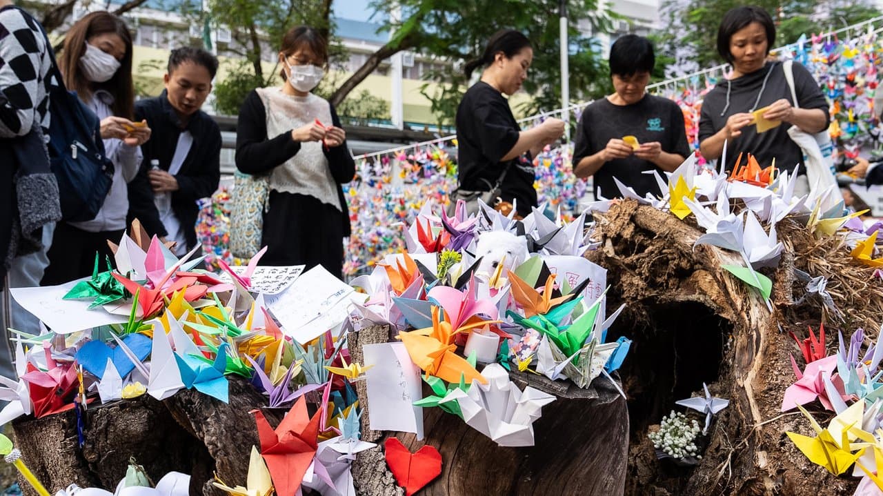 People place paper cranes near the site of the fire at Wang Fuk Court