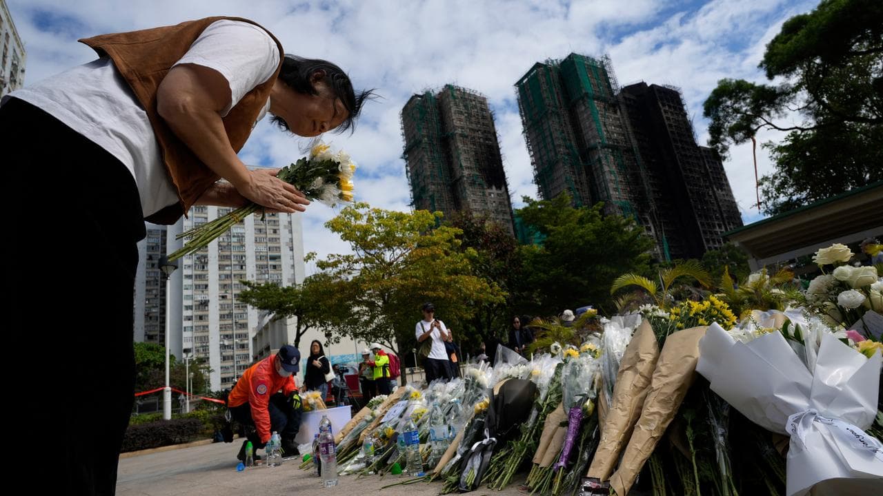 A woman offers flowers near the site of a fire at Wang Fuk Court