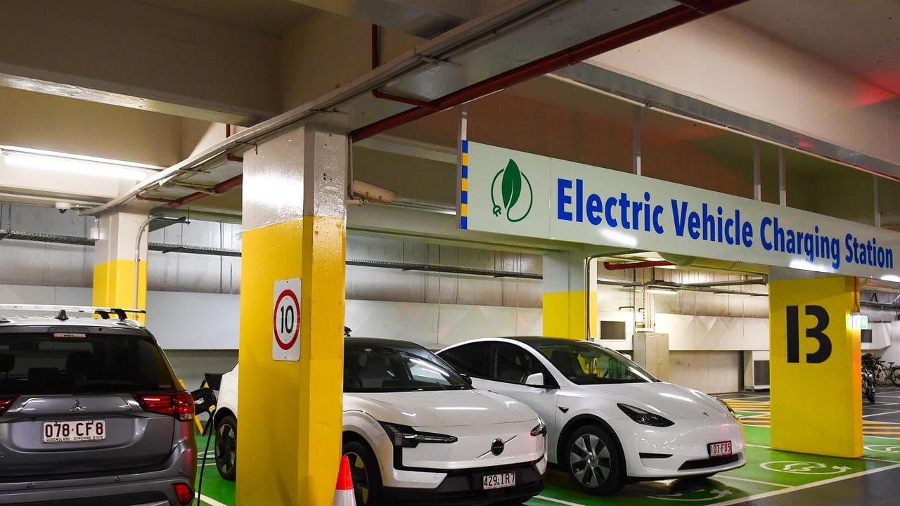 Electric vehicles being charged at a station in a parking garage.