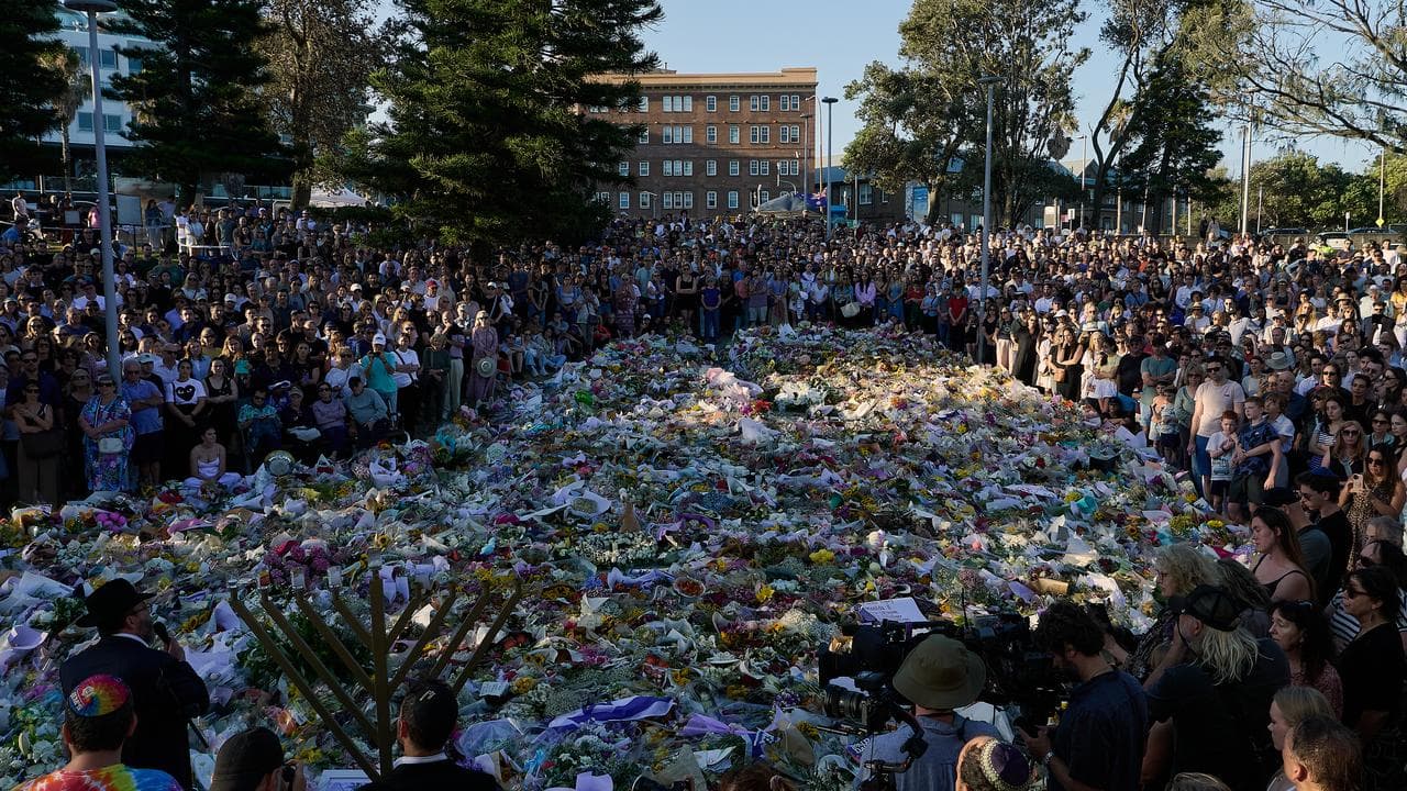 A crowd in front of a makeshift memorial at Bondi Beach.