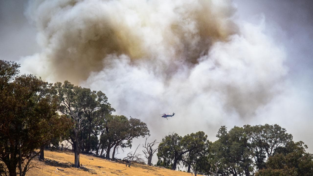 A firefighting helicopter flies near a bushfire